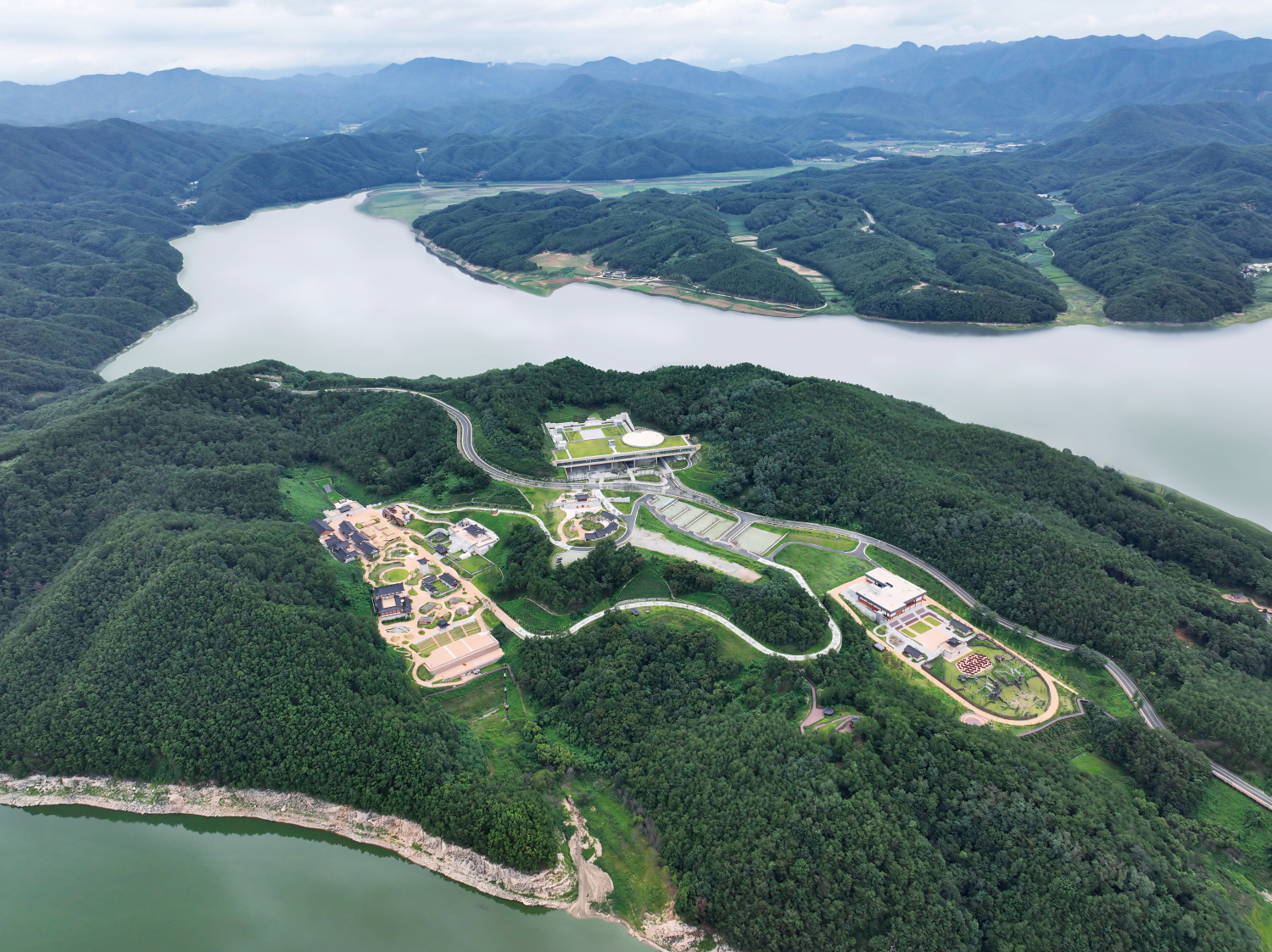 울창한 숲에 둘러싸인 안동국제컨벤션센터와 한국문화테마파크를 안동호 물길이 휘감은 풍경.